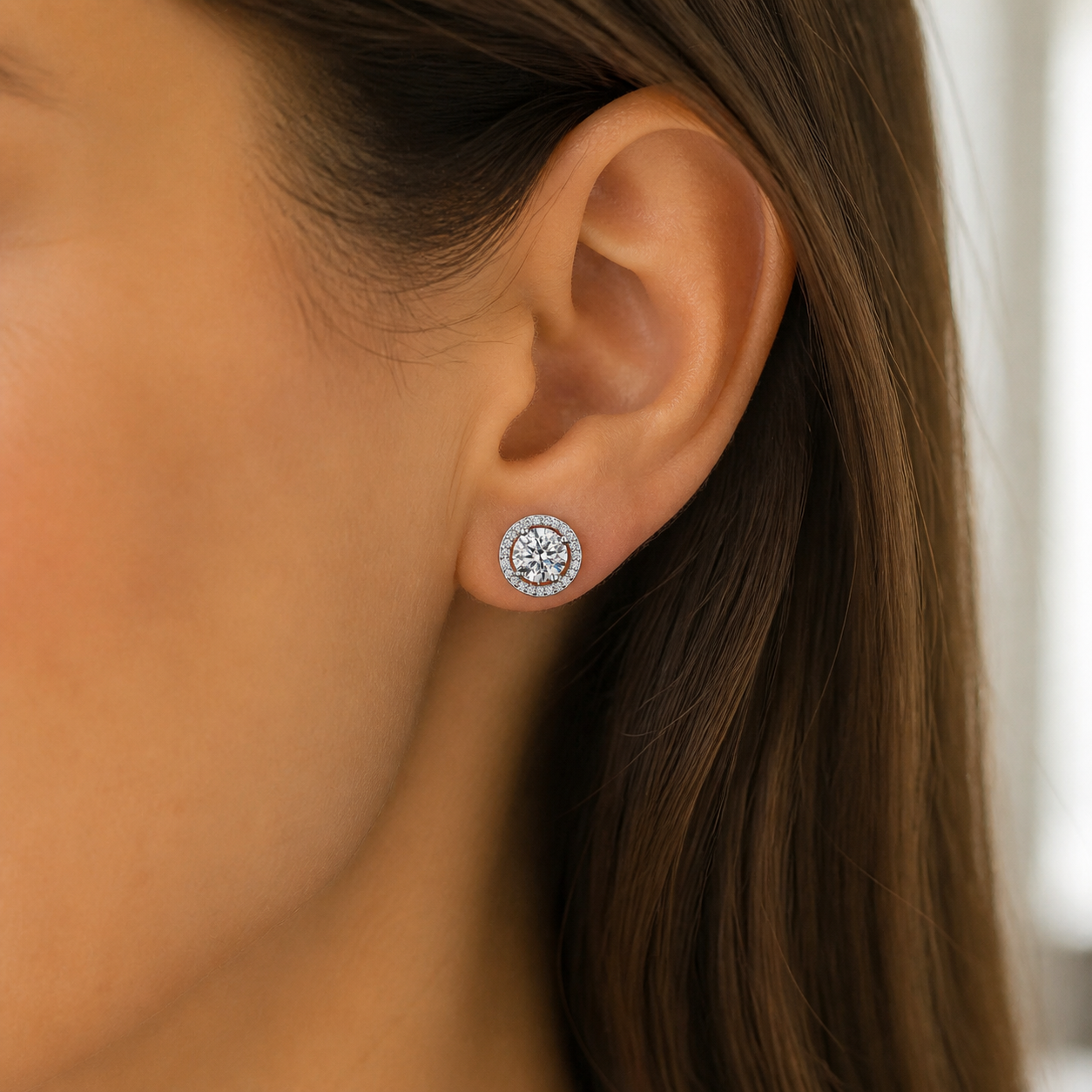 Round halo moissanite stud earring shown at a natural scale on the ear