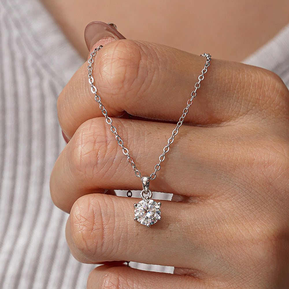 Round moissanite solitaire pendant necklace worn against a hand
