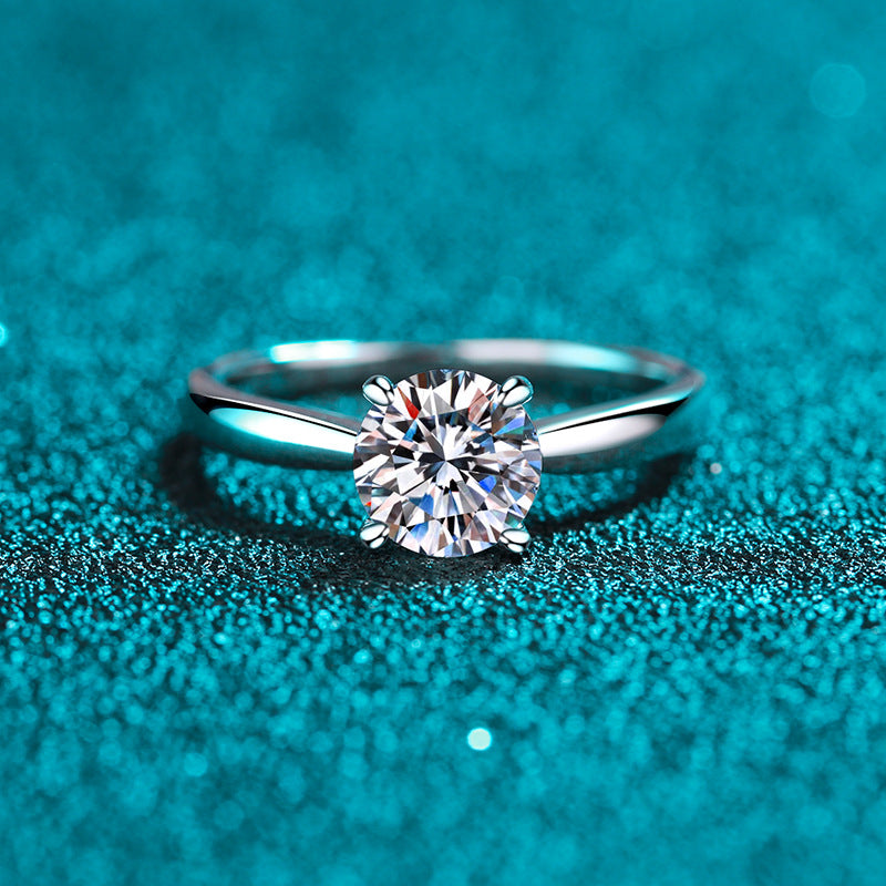 Front view of a round moissanite solitaire in a classic four-prong silver setting