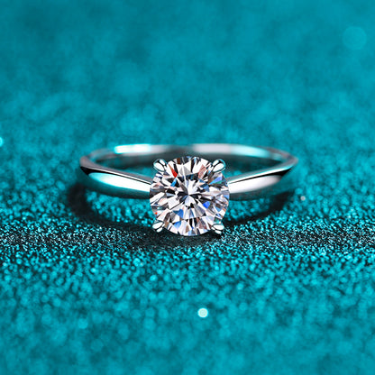 Front view of a round moissanite solitaire in a classic four-prong silver setting